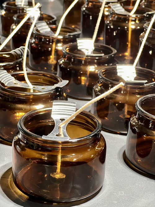 Rows of amber candle jars with wicks